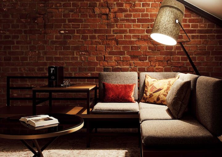 Gaswerk Hotel Hamburg Zimmer L Loft 1 L-Loft mit Sitzbereich, Stehlampe und sichtbarer Backsteinwand
