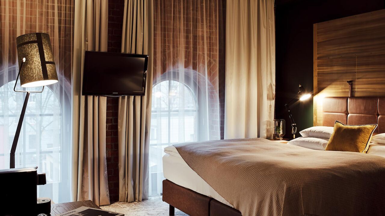 Gastwerk Hotel Hamburg S Loft Zimmer 3 Bett, große Fensterfront mit Backsteinwand, Fernseher und Stehlampe