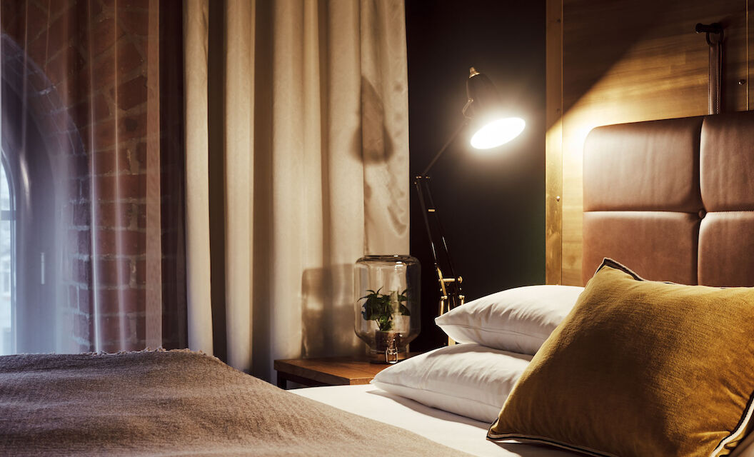 Gastwerk Hotel Hamburg S Loft Zimmer 4 Gemütliches Bett im S-Loft von der Seite mit Nachttischlampe
