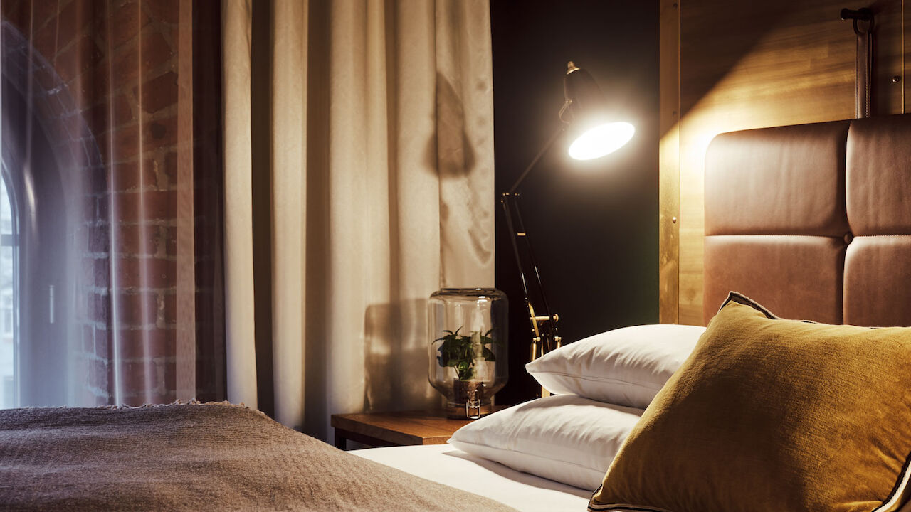 Gastwerk Hotel Hamburg S Loft Zimmer 4 Gemütliches Bett im S-Loft von der Seite mit Nachttischlampe