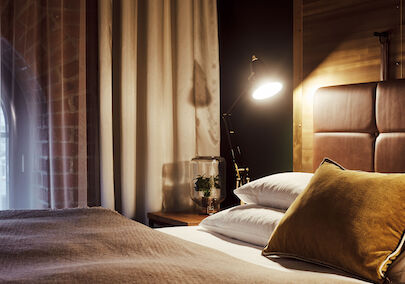 Gastwerk Hotel Hamburg S Loft Zimmer 4 Gemütliches Bett im S-Loft von der Seite mit Nachttischlampe