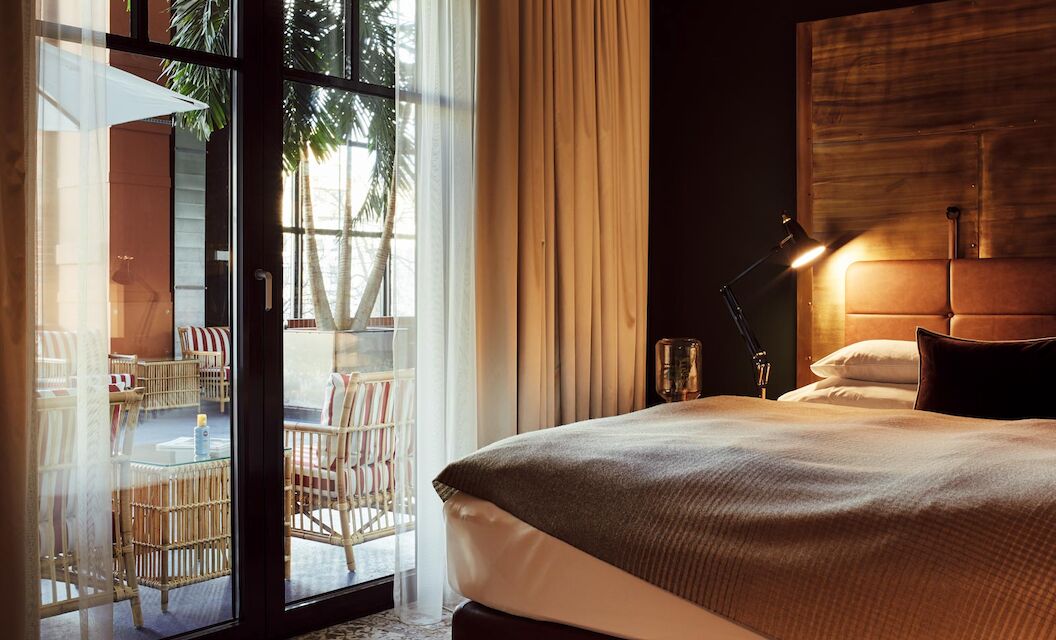 Gastwerk Hotel Hamburg S Loft Atrium Zimmer 3 Bett und große Fensterfront mit Blick auf das blaue Atrium im S-Loft