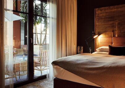 Gastwerk Hotel Hamburg S Loft Atrium Zimmer 3 Bett und große Fensterfront mit Blick auf das blaue Atrium im S-Loft