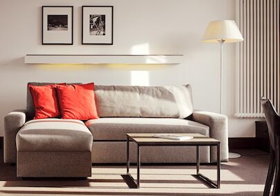 Gastwerk Hotel Hamburg Xxl Loft Zimmer 12 Graues Sofa mit Recamiere und roten Kissen, davor ein Beistelltisch