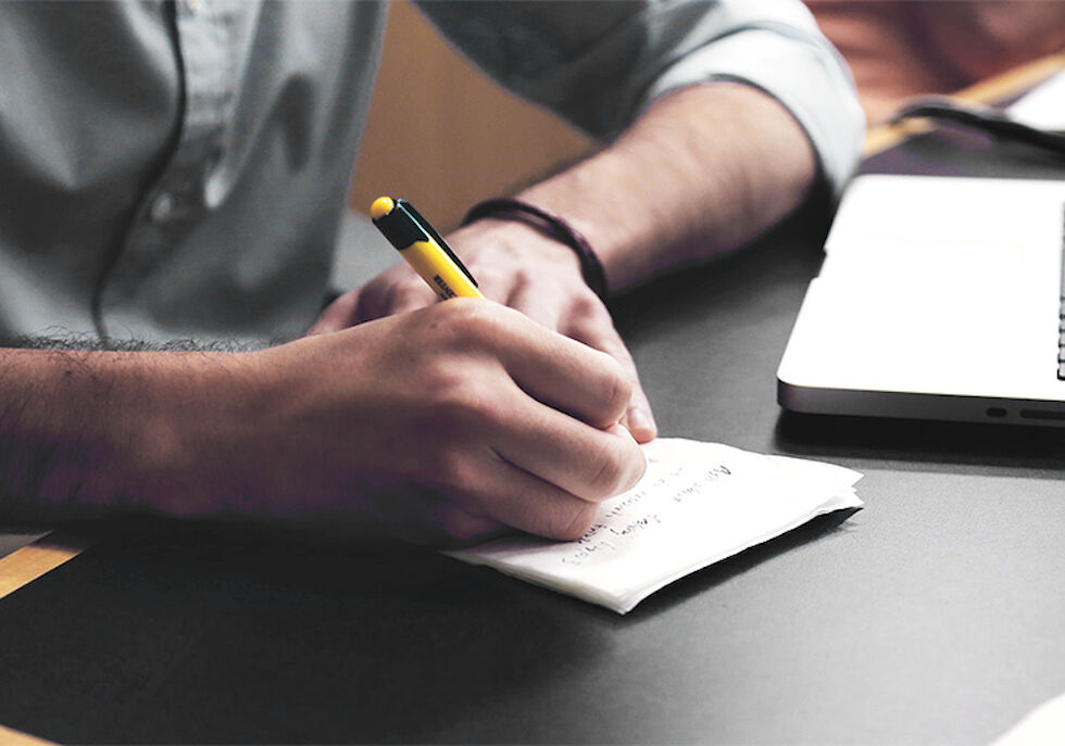 Writing Gastwerk Ein Mann am Schreibtisch der etwas auf einen Zettel schreibt