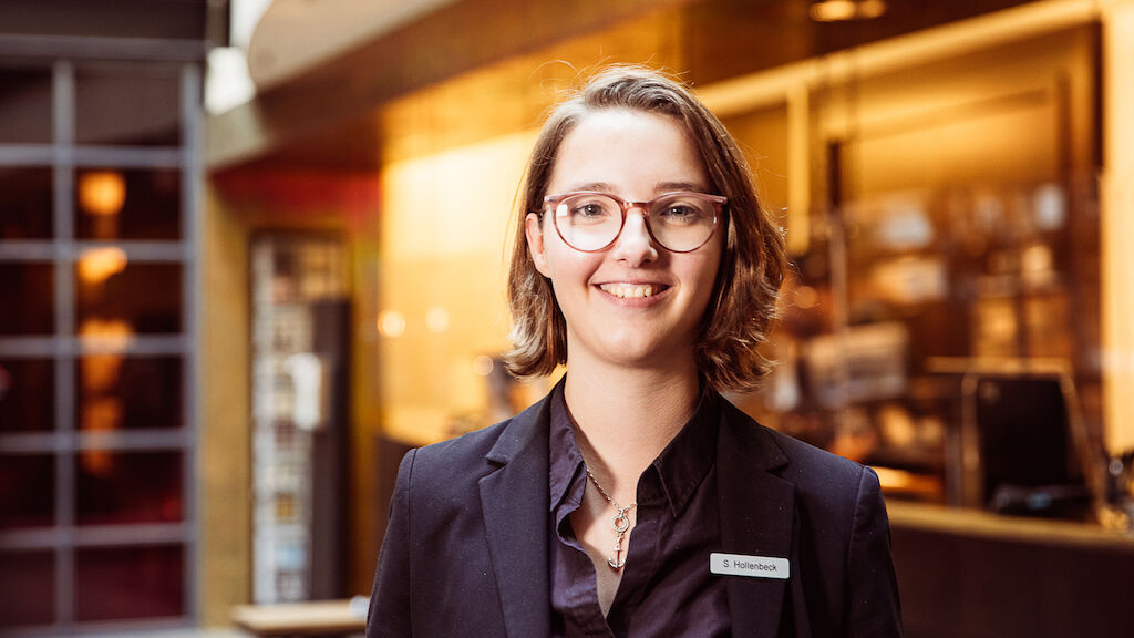 Front Office Mitarbeiterin aus dem Gastwerk Hotel vor der Rezeption