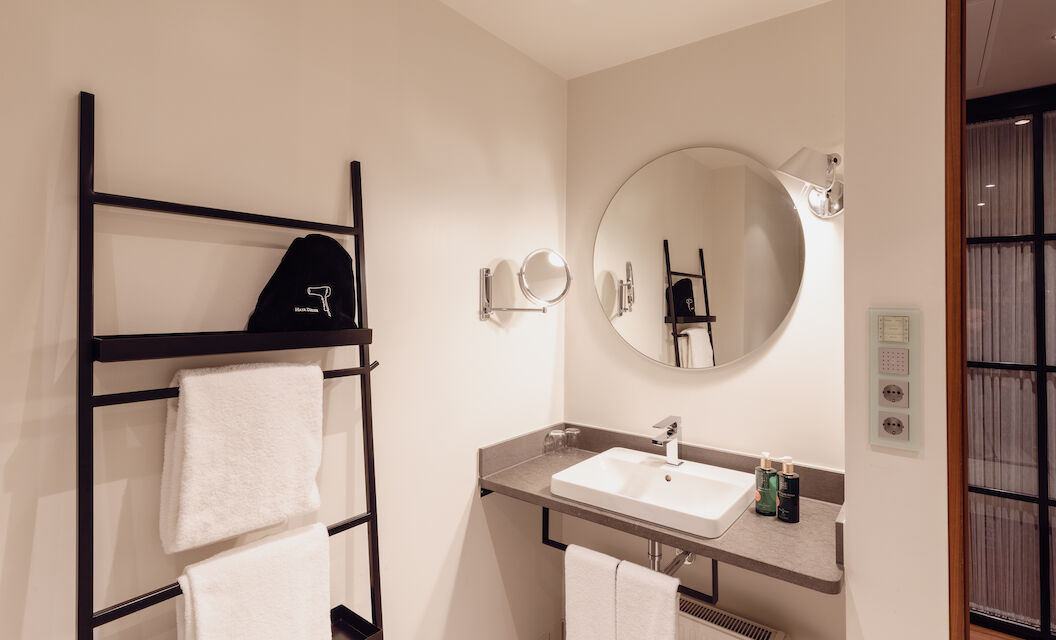 Gastwerk Hotel Hamburg M Loft Superior 18 Das Badezimmer aus dem Gastwerk Hotel Hamburg M Loft Superior mit einem runden Spiegel.
