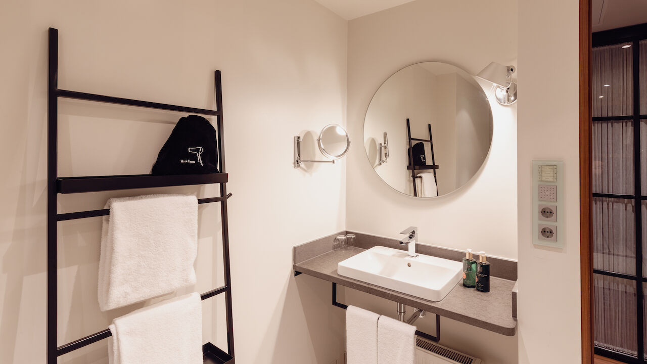 Gastwerk Hotel Hamburg M Loft Superior 18 Das Badezimmer aus dem Gastwerk Hotel Hamburg M Loft Superior mit einem runden Spiegel.