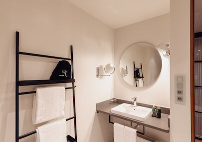 Gastwerk Hotel Hamburg M Loft Superior 18 Das Badezimmer aus dem Gastwerk Hotel Hamburg M Loft Superior mit einem runden Spiegel.