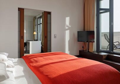 Gastwerk Hotel Hamburg Zimmer Xxl Loft 510 06 Schlafzimmer im XXL-Loft mit Bett, Fernseher und Terrasse mit Liegestühlen
