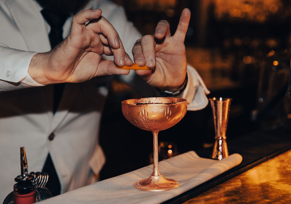 Gastwerk Hotel Hamburg Bar Mangold 11 Messing Martiniglas über dem eine Zitronenzeste ausgedrückt wird