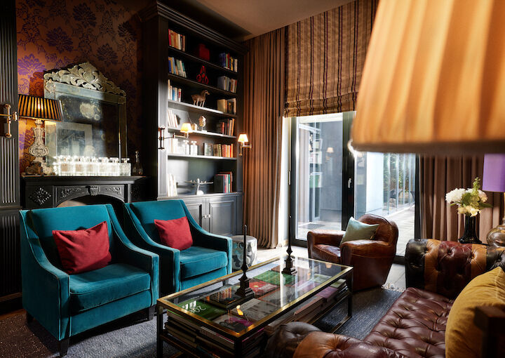 Library with two blue armchairs, leather armchairs and a chesterfiel couch