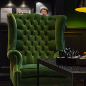 Green upholstered armchair in front of table with chessboard in Private Library