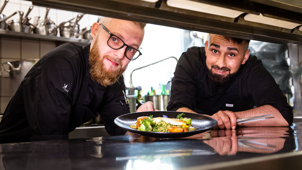 Zwei Köche zeigen stolz ein frisch zubereitetes Gericht