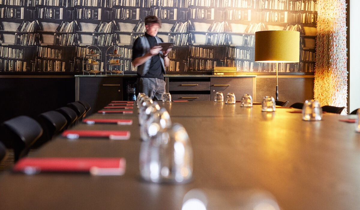 View along large table in Clubroom XL, man with tablet in background