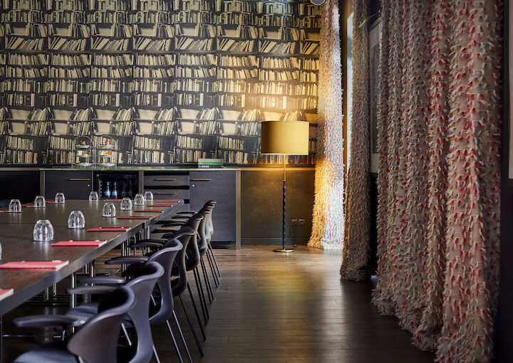 View along row of chairs with elegant wallpaper and gold lamp