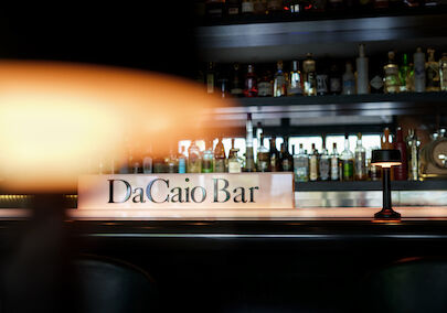 Lamp foreground with spirits rack and DaCaio Bar logo behind