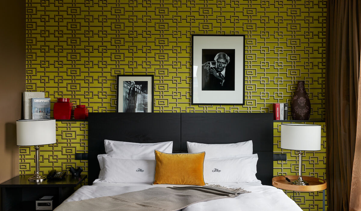 Buchwerk Hamburg Gästezimmer Juniorsuite 01 Frontalansicht eines Betts vor gemusterter grüner Tapete