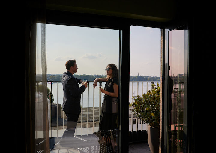Couple stands on S Room terrace enjoying the view of the Alster