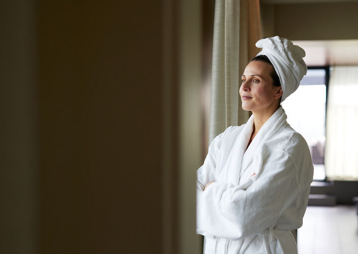 Women in a bathrobe looks out a window