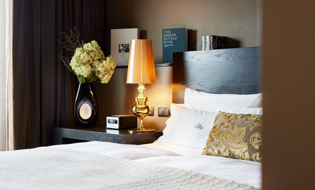 The George Hotel Hamburg Zimmer The George Suite 02 Side view of headboard with golden lamp and books in the background
