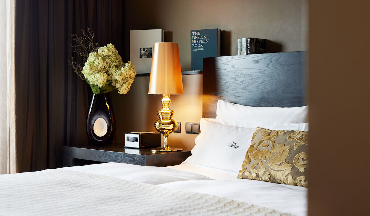 Buchwerk Hamburg Gästezimmer Buchwerk Suite 02 Seitenansicht des Doppelbett Kopfteils samt goldener Lampe sowie Büchern in Hintergrund