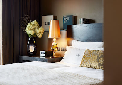 The George Hotel Hamburg Zimmer The George Suite 02 Side view of headboard with golden lamp and books in the background