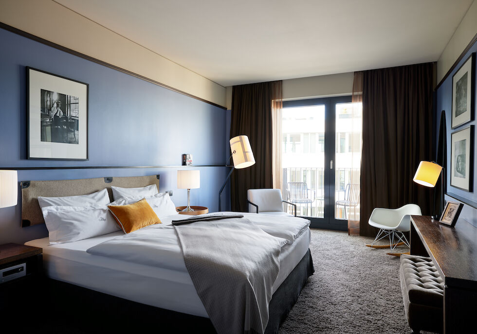 Double bed with gray bedspread and mustard cushion in the M-Room