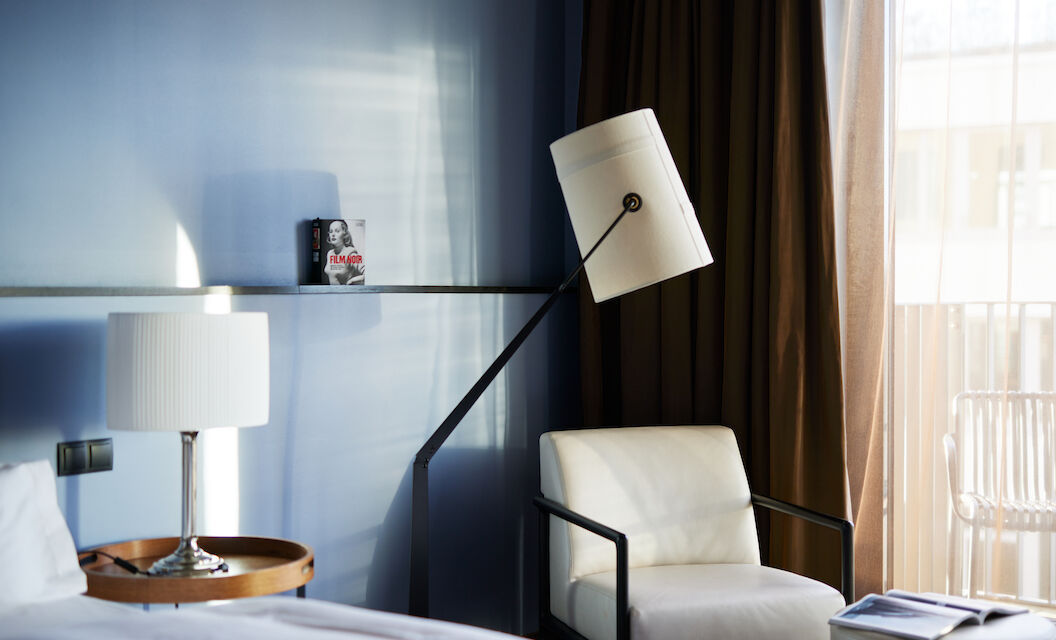 The George Hotel Hamburg Zimmer M Room 05 White armchair next to floor lamp against blue wall in M-Room