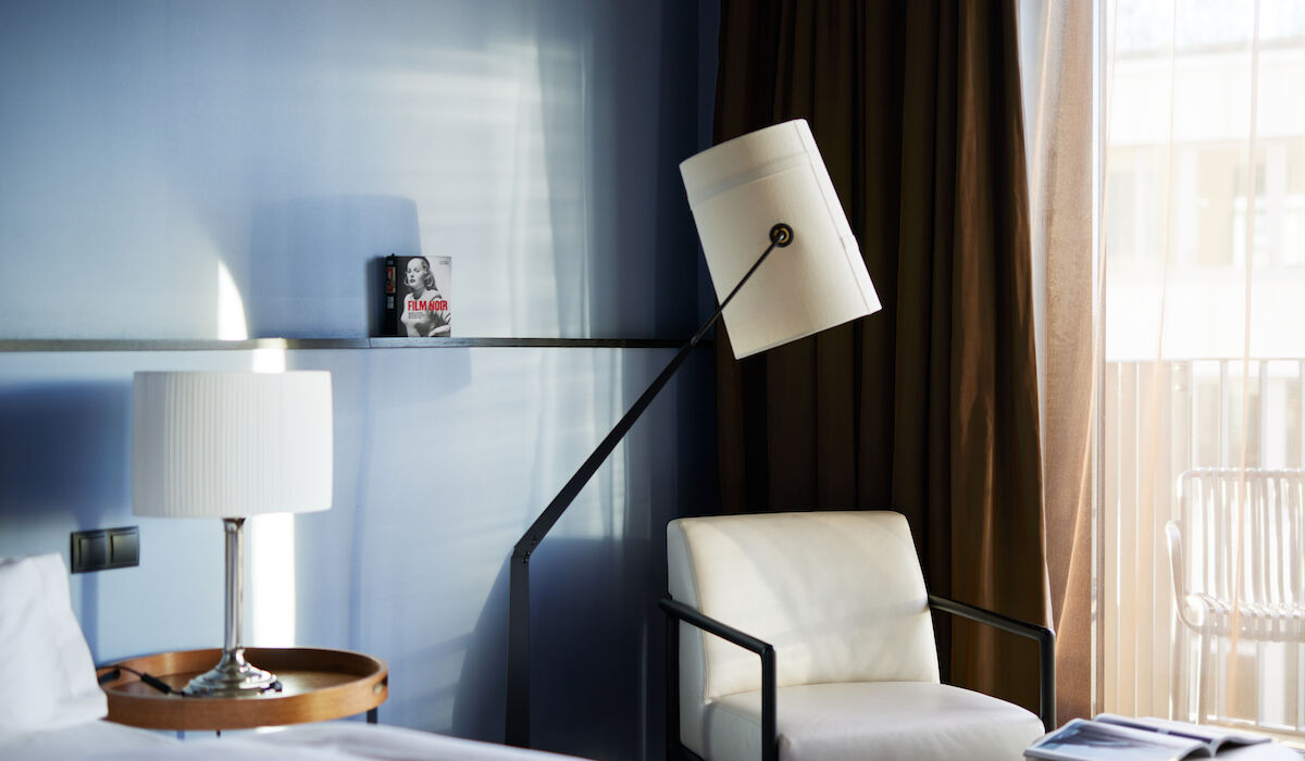 Buchwerk Hamburg Gästezimmer M Room 05 Weißer Sessel samt Stehlampe vor blauer Wand im M-Room