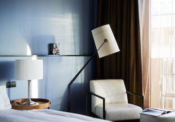 White armchair next to floor lamp against blue wall in M-Room
