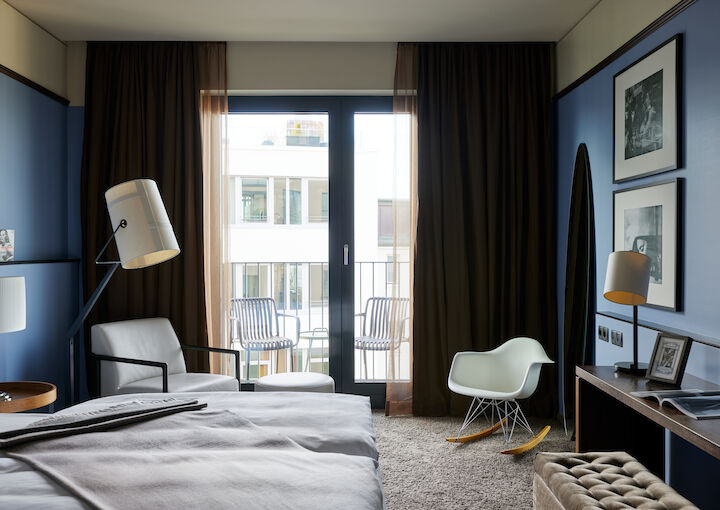 Double bed in foreground, white armchair and Eames chair in background