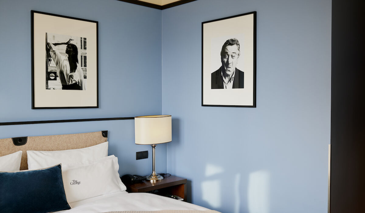 Buchwerk Hamburg Gästezimmer S Room 04 Doppelbett vor blauer Wand samt Foto eines Mannes an der Wand