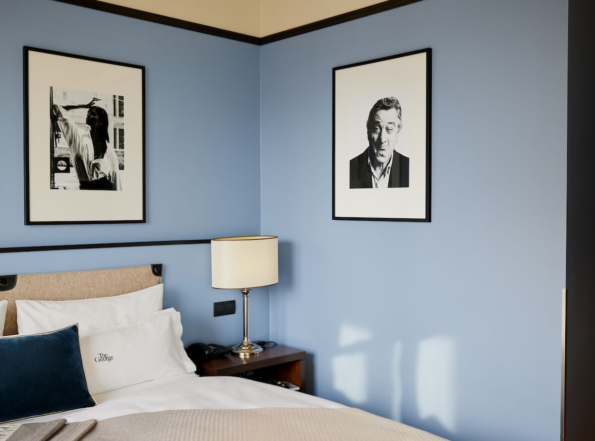 Blue wall behind double bed with a man's photo on it