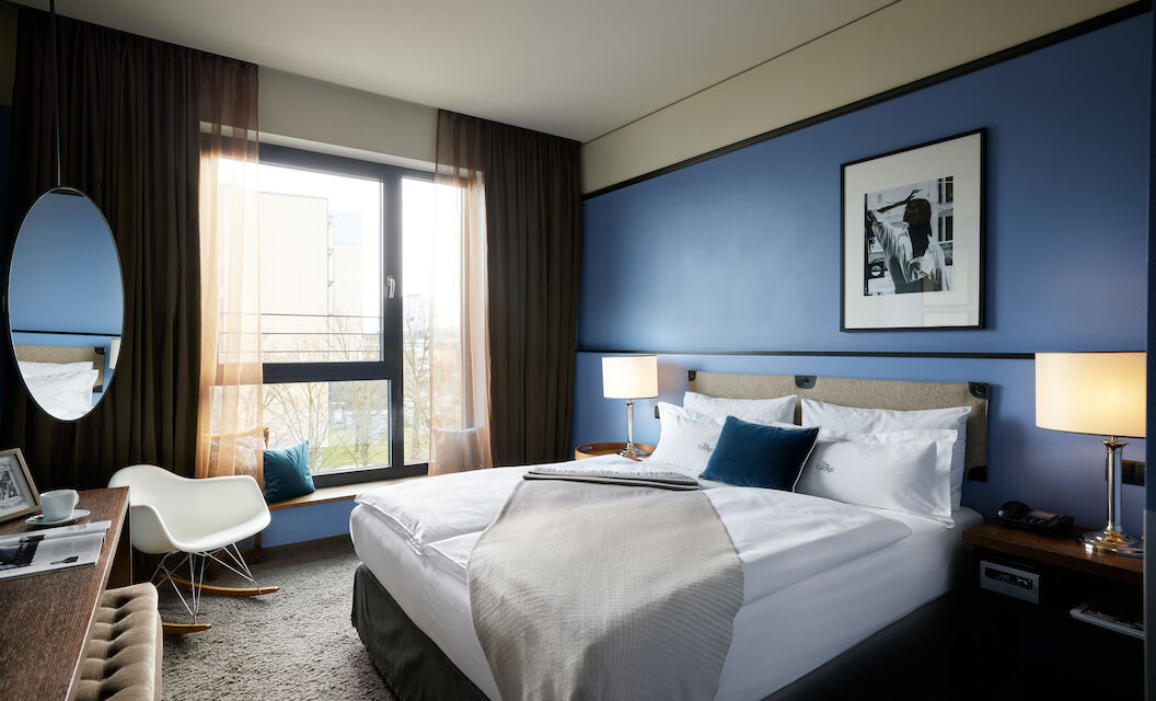 The George Hotel Hamburg Zimmer S Room 01 Kingsize bed in front of blue wall with wall decor in S-Room.