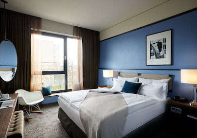 The George Hotel Hamburg Zimmer S Room 01 Kingsize bed in front of blue wall with wall decor in S-Room.