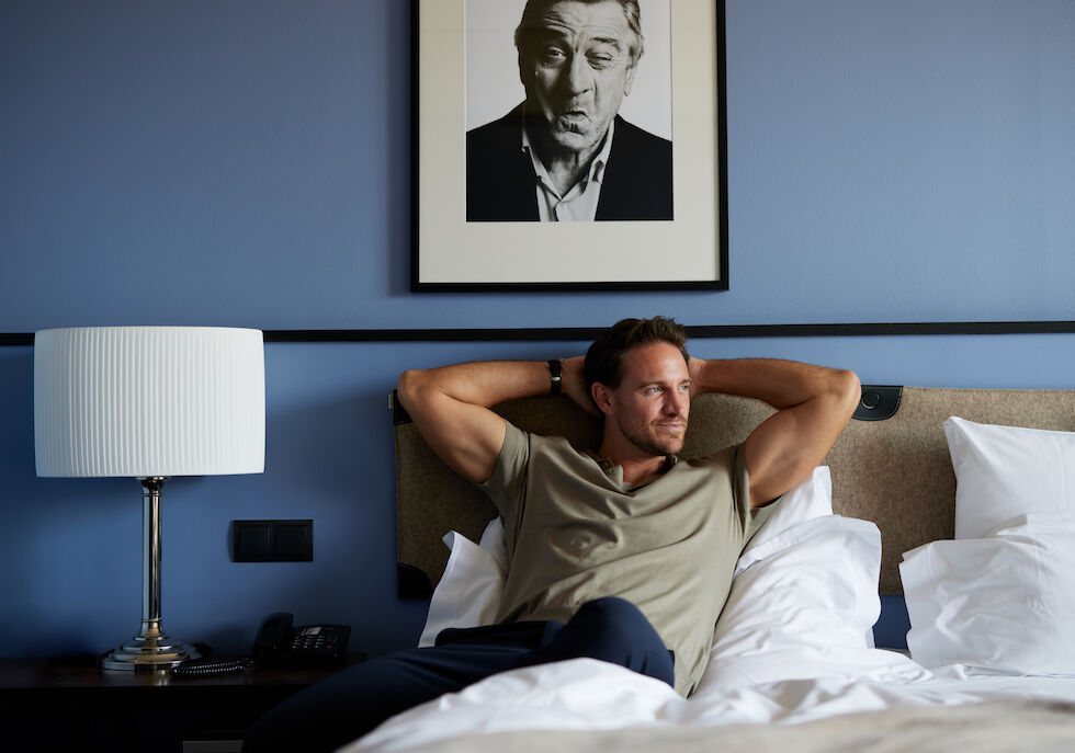 Man relaxing in bed in the M-Room at The George Hotel
