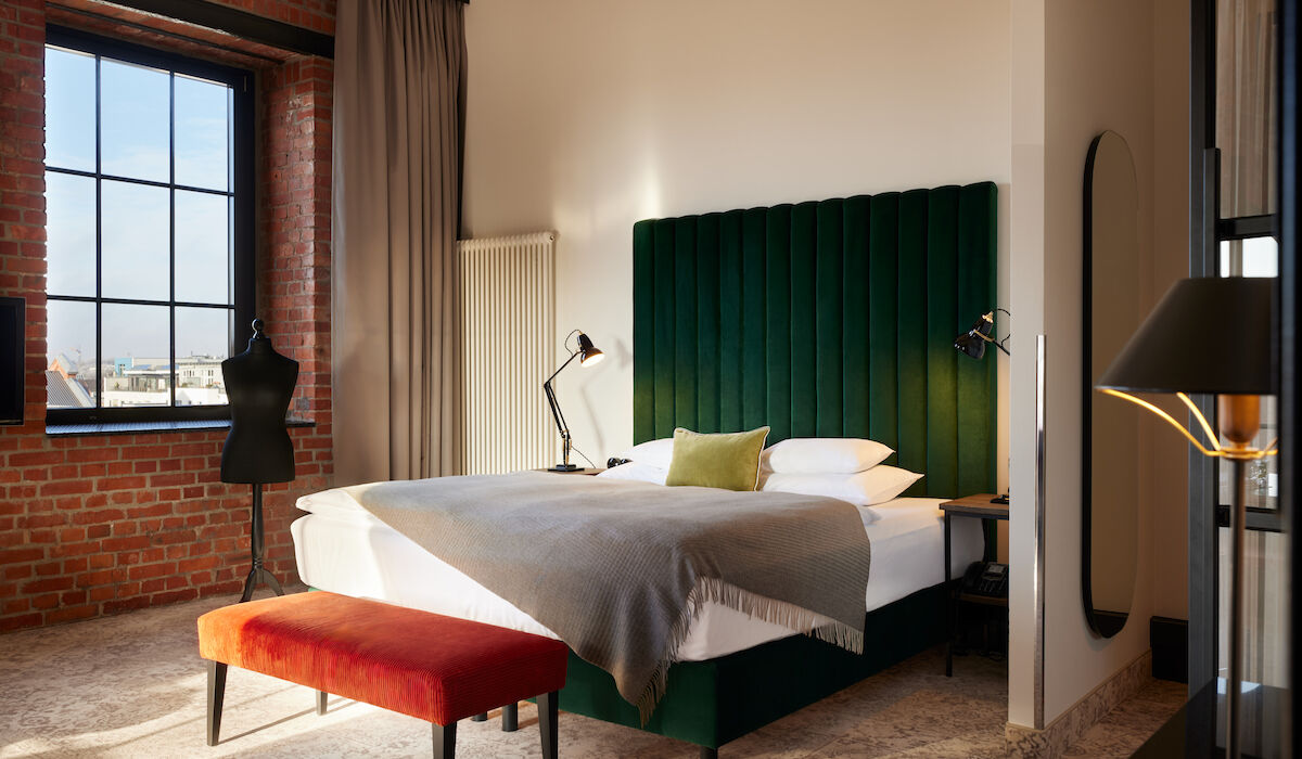 Gastwerk Hotel Hamburg Zimmer Xl Loft 554 01 Kingsizebett mit grünem Samtkopfteil und Schneidepuppe vor Backsteinwand