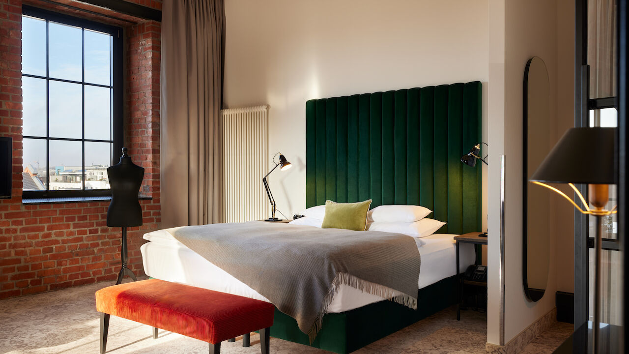 Gastwerk Hotel Hamburg Zimmer Xl Loft 554 01 Kingsizebett mit grünem Samtkopfteil und Schneidepuppe vor Backsteinwand