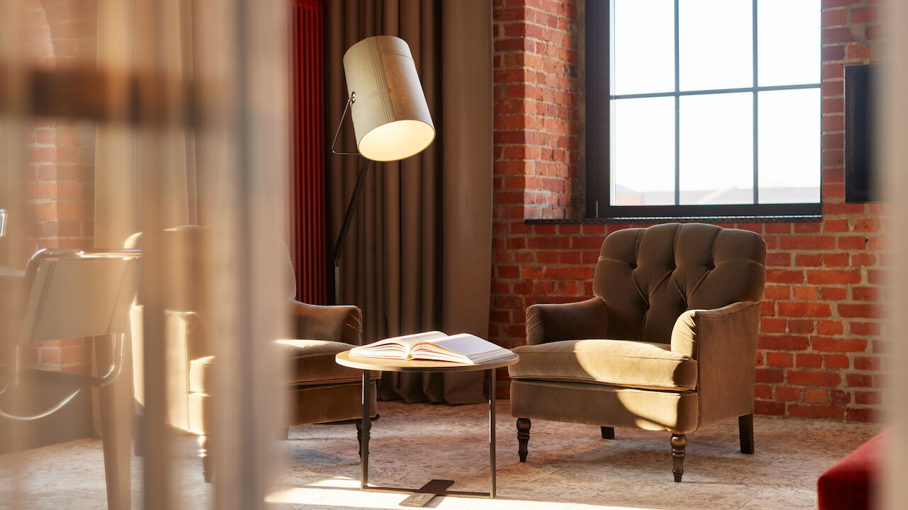 Gastwerk Hotel Hamburg Zimmer Xl Loft 554 03 Edle Sessel, Stehlampe und Tisch mit Buch vor Backsteinwand im XL Loft