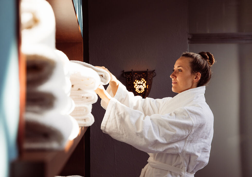 Perfekter Tag 31 Frau nimmt ein Handtuch aus dem Regal im Cosy Spa