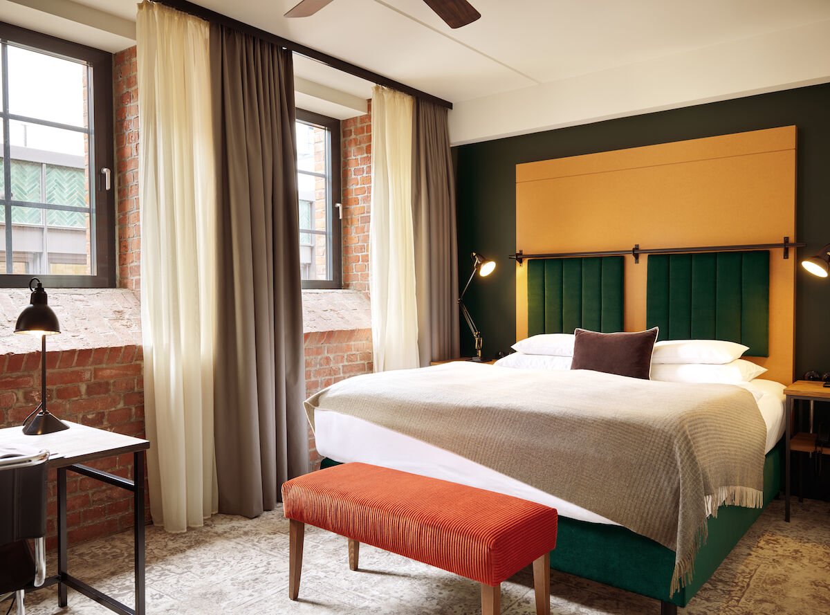 Gastwerk Hotel Hamburg Zimmer S Loft 01 Doppelbett im S-Loft mit dunkelroter Sitzbank davor.