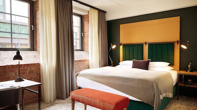Doppelbett im S-Loft mit dunkelroter Sitzbank davor.