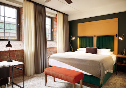 Gastwerk Hotel Hamburg Zimmer S Loft 01 Doppelbett im S-Loft mit dunkelroter Sitzbank davor.
