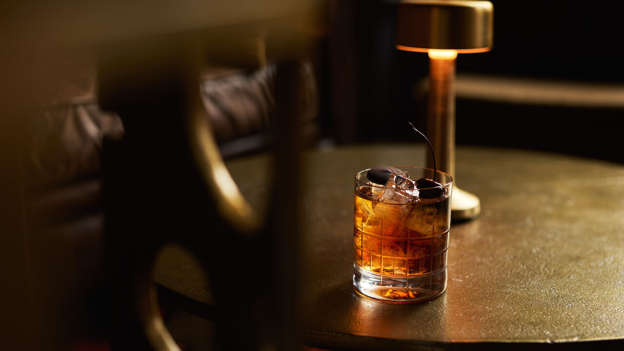 Drink im Tumblerglas auf goldenem Couchtisch