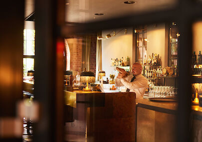 Gastwerk Hotel Hamburg Bar Mangold Atmosphaere 018 Barkeeper mixt hinter dem Tresen der Bar Mangold einen Drink.