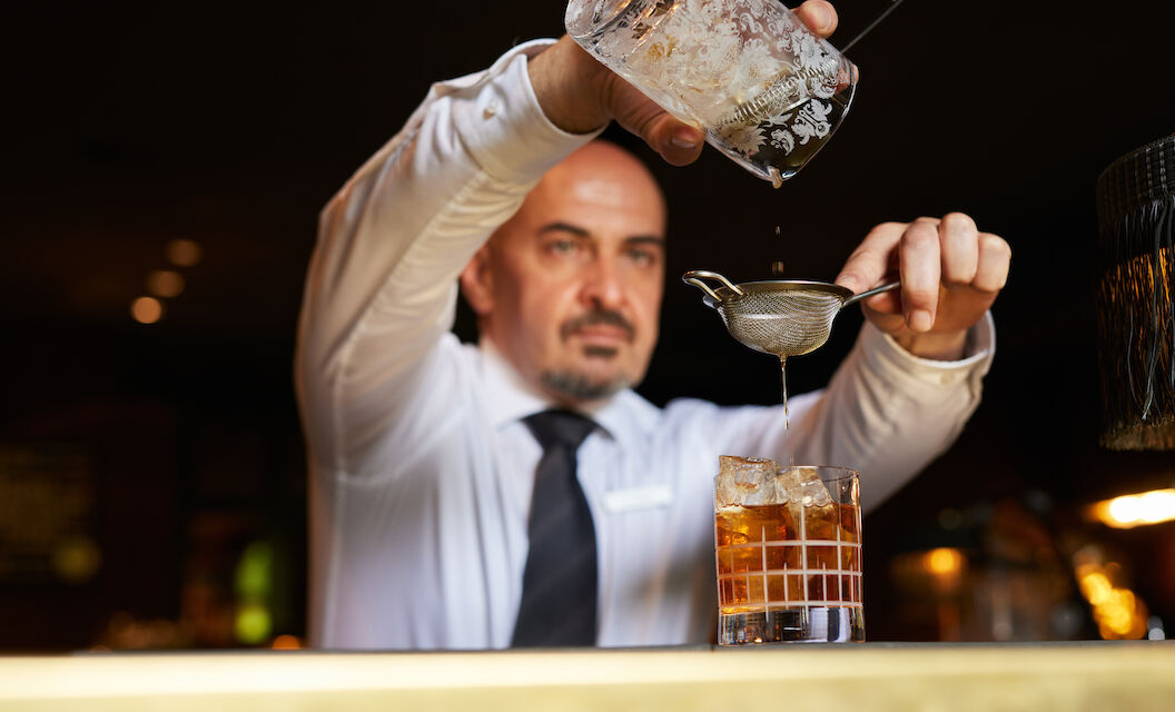 Gastwerk Hotel Hamburg Bar Mangold Atmosphaere 019 Barkeeper gießt einen Drink in ein Tumblerglas.