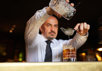 Gastwerk Hotel Hamburg Bar Mangold Atmosphaere 019 Barkeeper gießt einen Drink in ein Tumblerglas.