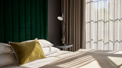Sonnenschein fällt durch die großen Fenster auf das Bett im Loft