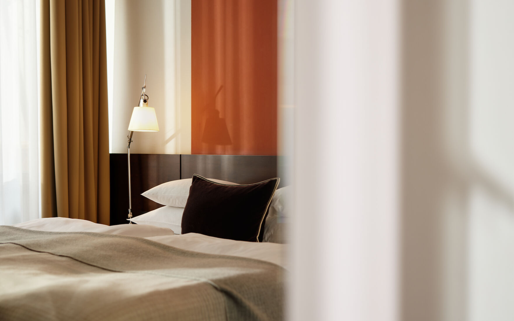 Gastwerk Hotel Hamburg Zimmer M Loft 016 02 Seitlicher Blick auf Doppelbett im M Loft mit Gardine im Vordergrund